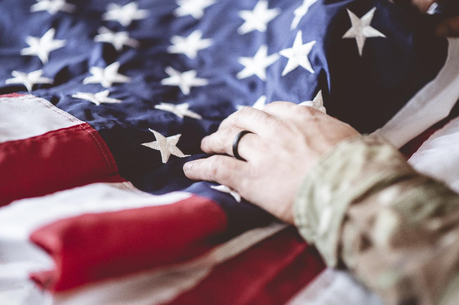 Close-up of a service member's hand resting on the American flag, symbolizing military service and eligibility for the VA Home Loan Program.