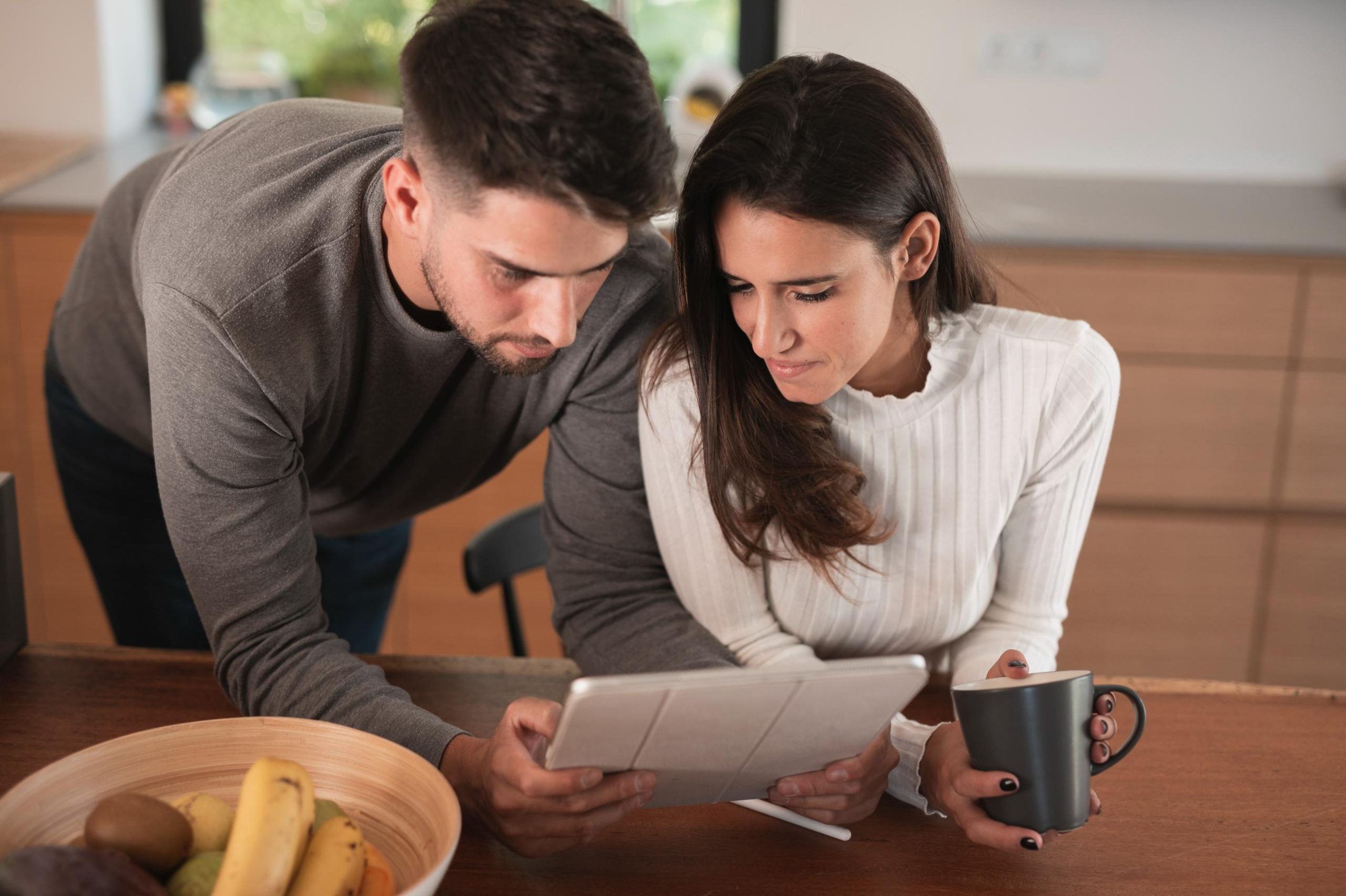 Couple reviewing home financing options on a tablet at their kitchen table while researching USDA home loans.