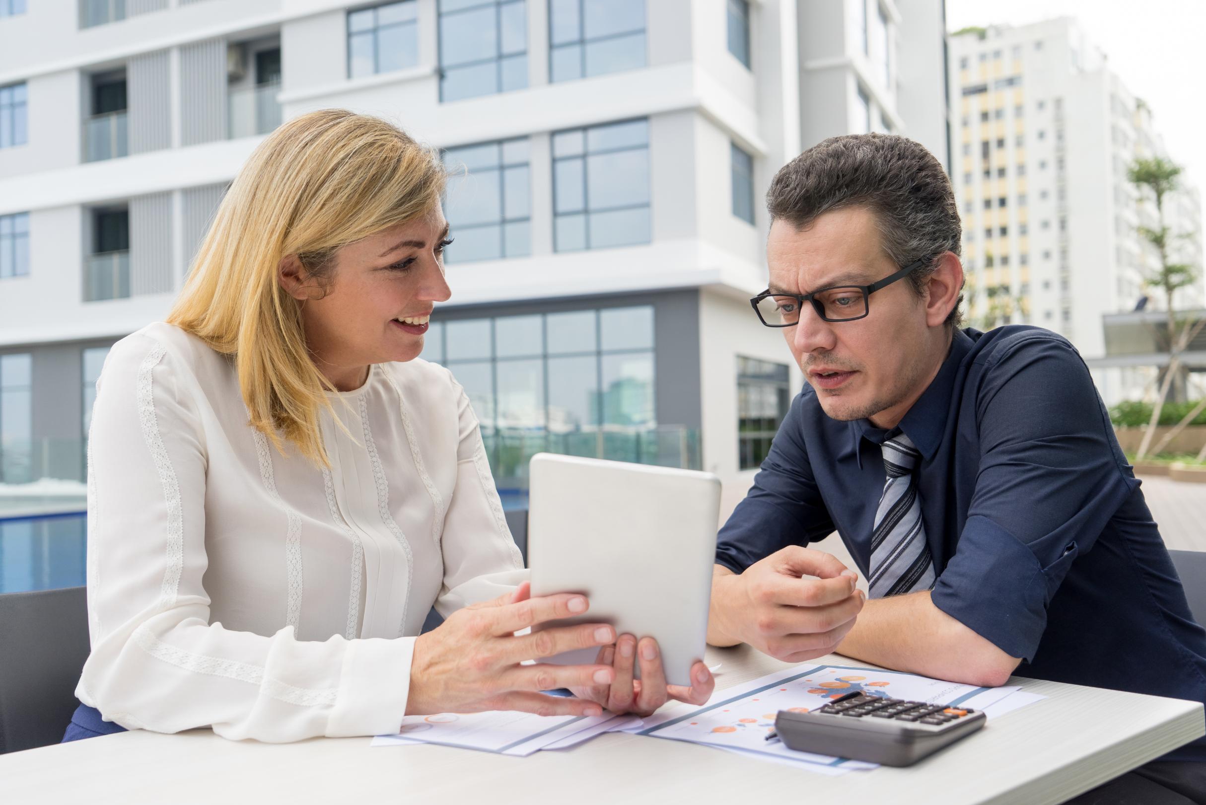 Mortgage professional discussing USDA loan qualifications in Texas with a homebuyer using financial documents and a tablet.