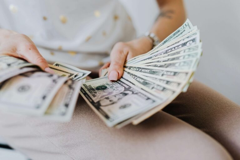 Person counting a stack of U.S. dollar bills, symbolizing cash-out refinance opportunities available in Texas.