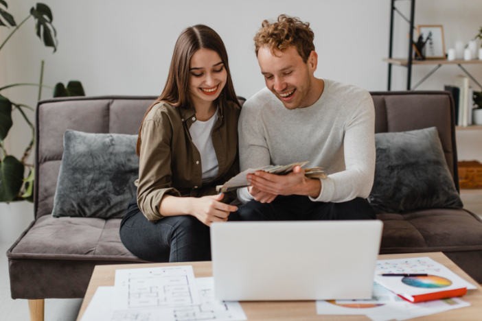 Couple reviewing property plans with cash and laptop while researching DSCR loan options and rental property financing.