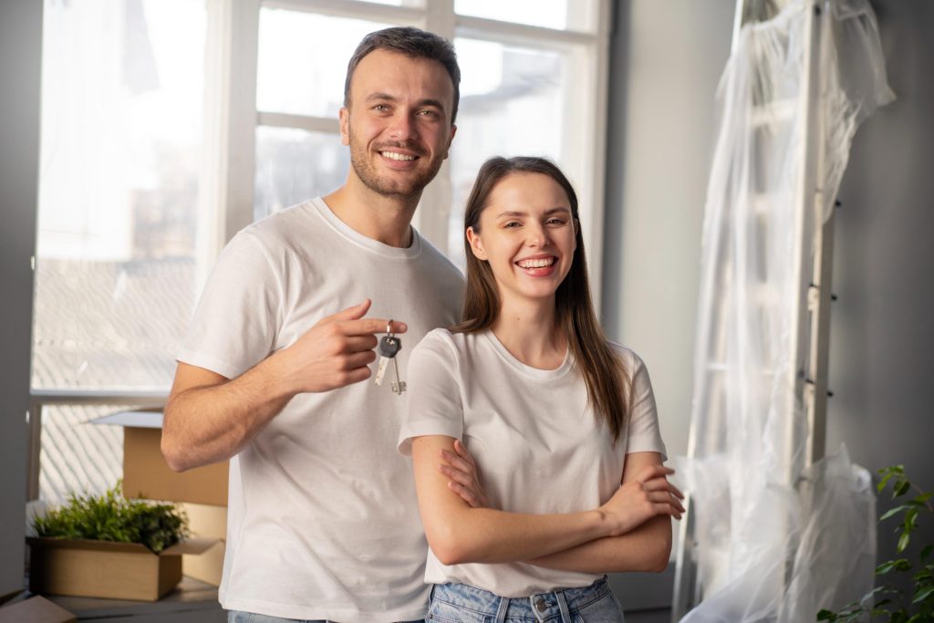A happy couple standing in their new home holding house keys, symbolizing the process to buy a home in El Paso.