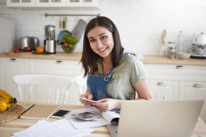 Self-employed woman reviewing financial documents and planning for a home loan application at her kitchen table.