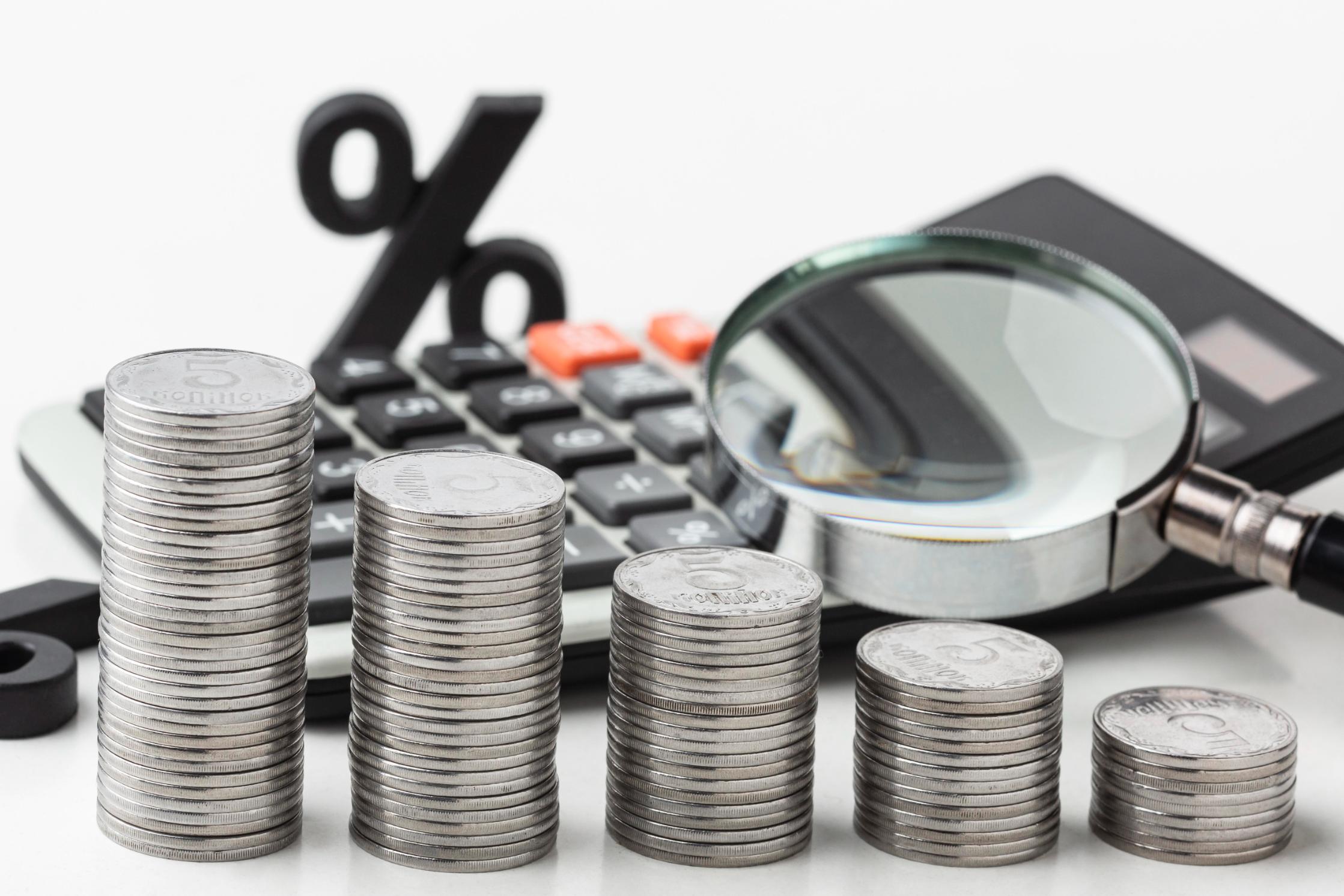 Stacks of coins with calculator and percent sign representing first time home buyer Texas costs, budgeting, and mortgage planning.